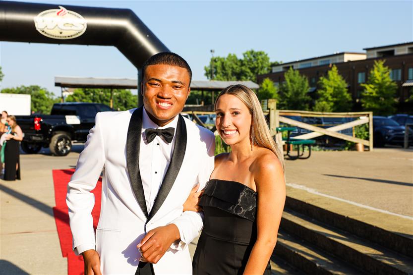 A young man and woman stand on the red carpet